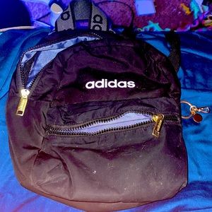 Black adidas mini backpack with white letters and gold zipper